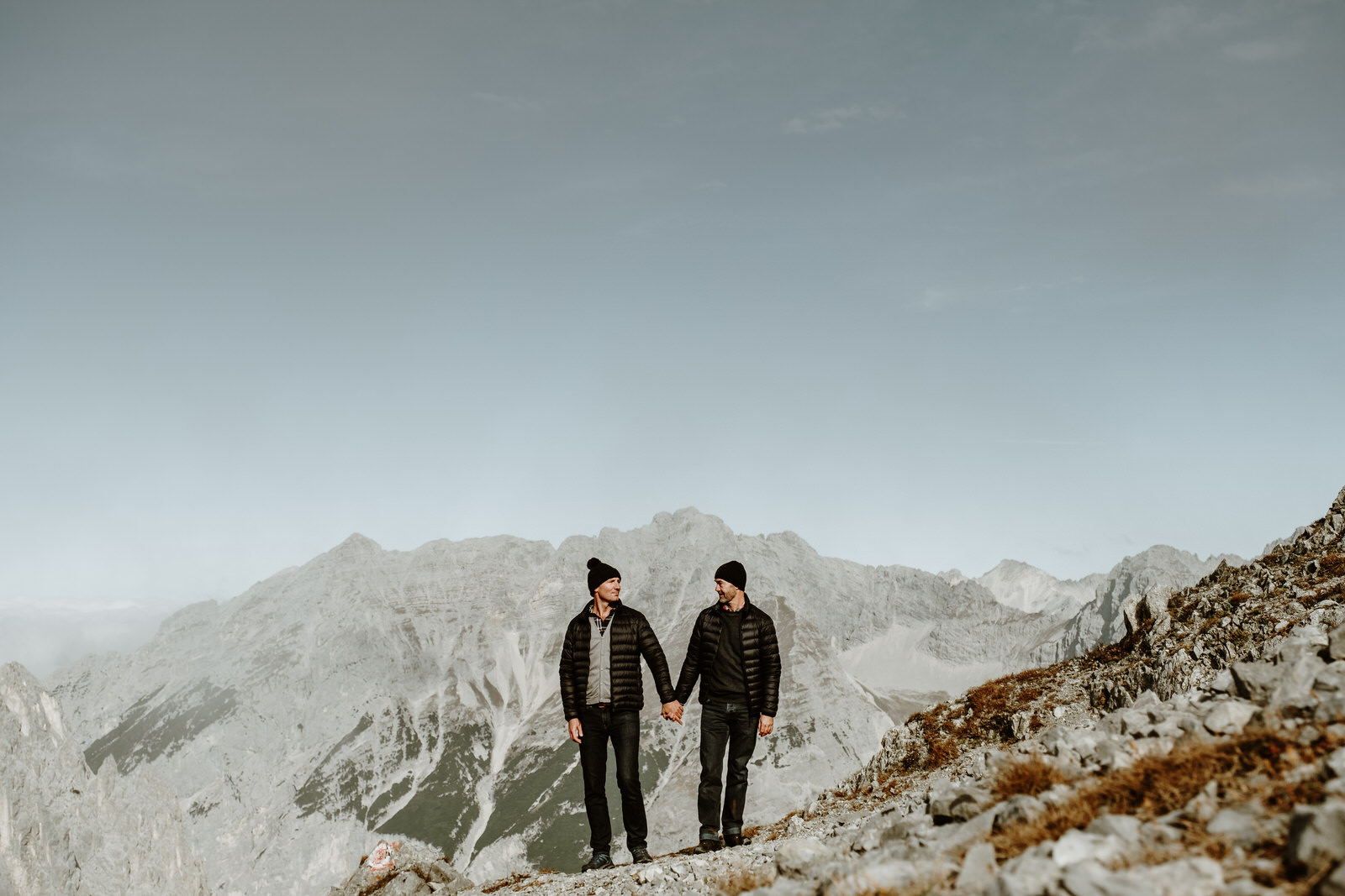 LGBTQ+ Elopement in Innsbruck with two groom, standing holding hands on the top of a mountain in Innsbruck Austria
