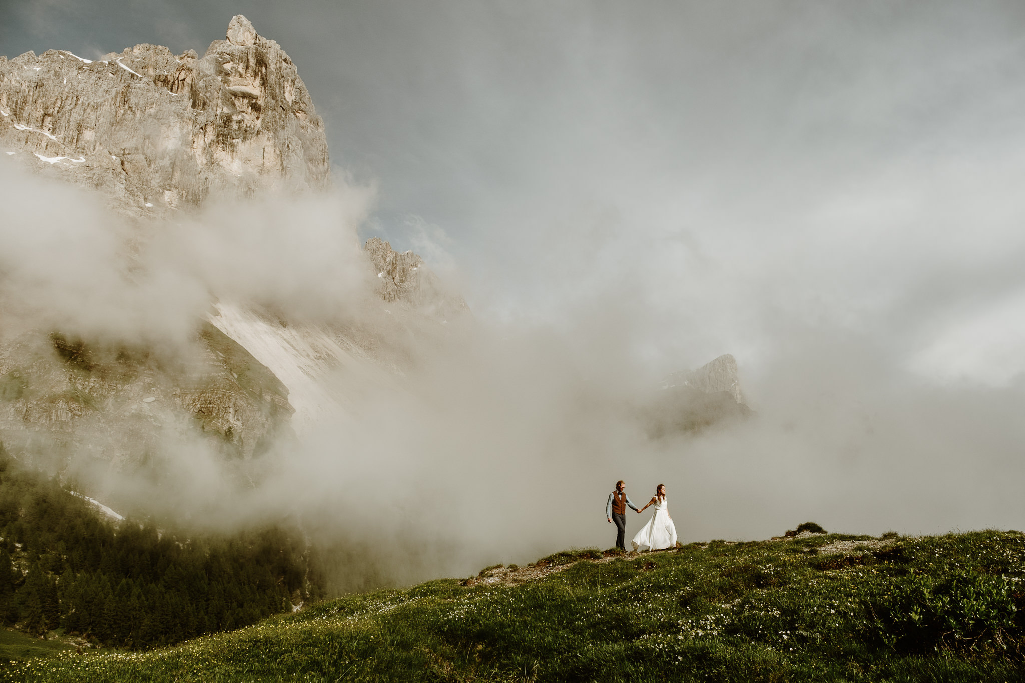 A couple hiking in a wedding dress and suit in the Dolomites. Photo by Wild Connections Photography