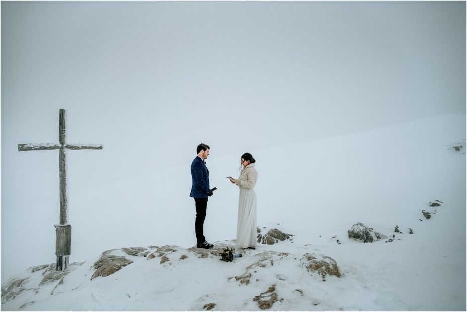 Bride and groom read their wedding vows on the top of a mountain in a snowstorm in Austria. Photos by Wild Connections Photography