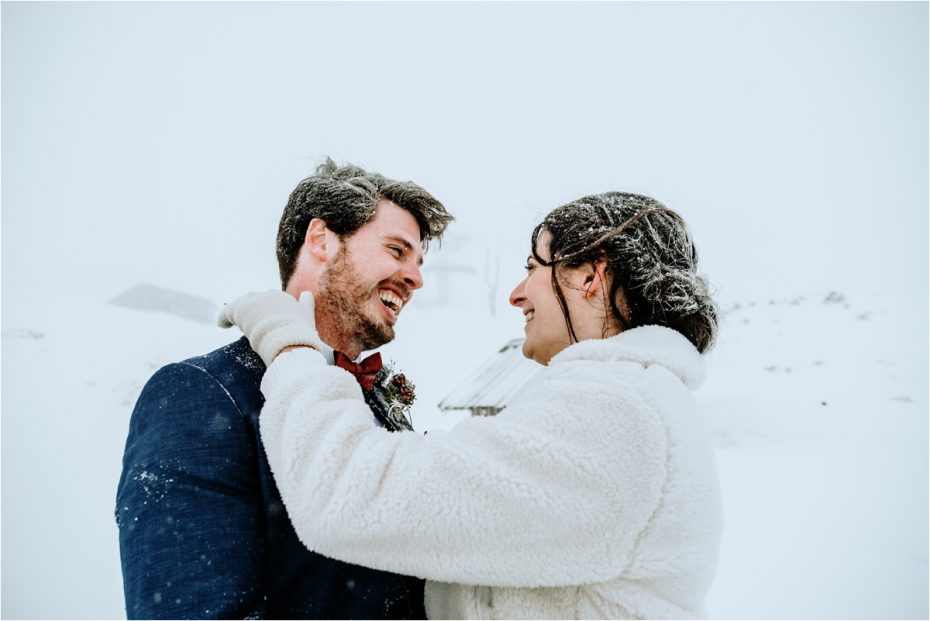 Bride and groom embrace, covered in snow, after their outdoor winter elopement ceremony in Austria. Photos by Wild Connections Photography