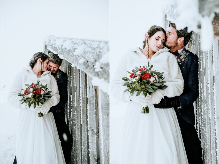 Bride and groom take shelter from the wind behind a wooden mountain hut. Photos by Wild Connections Photography