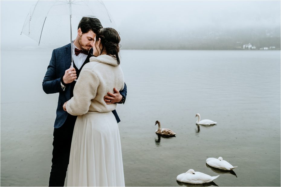 Swans swim on the lake behind the bride and groom after their elopement in Hallstatt Austria. Photos by Wild Connections Photography