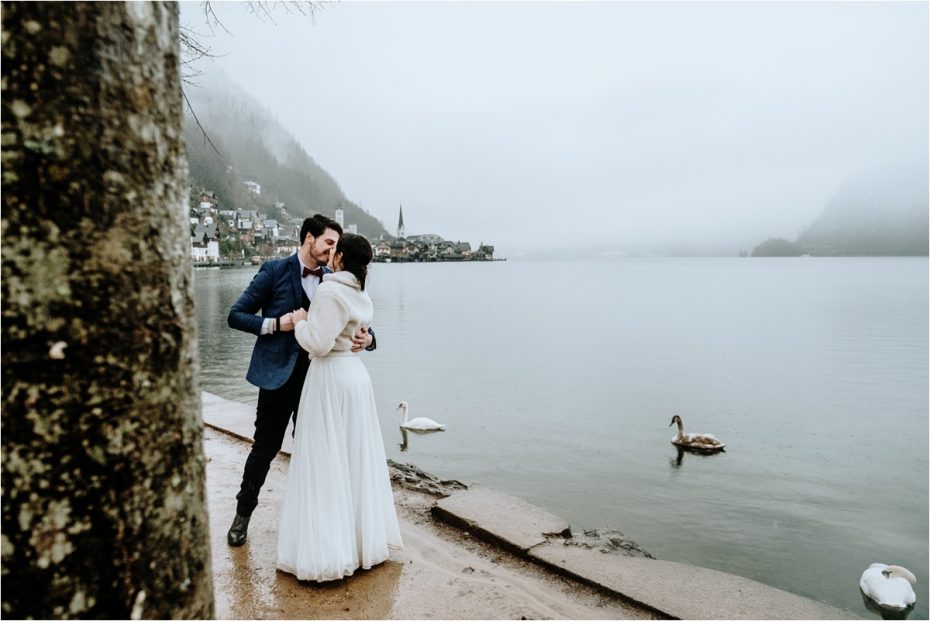 Anna & John kiss by the Hallstatt Lake on their wedding day. Photos by Wild Connections Photography
