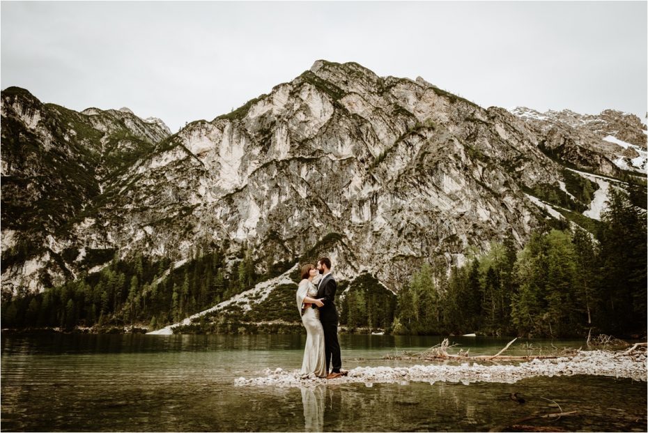 Posvatební oslava u jezera Braies v italských Alpách se zlatými svatebními šaty.  Foto od Wild Connections Photography