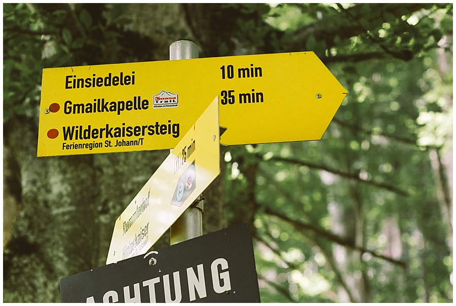 St Johann in Tirol Elopement a hiking trail sign in the woods by Wild Connections Photography