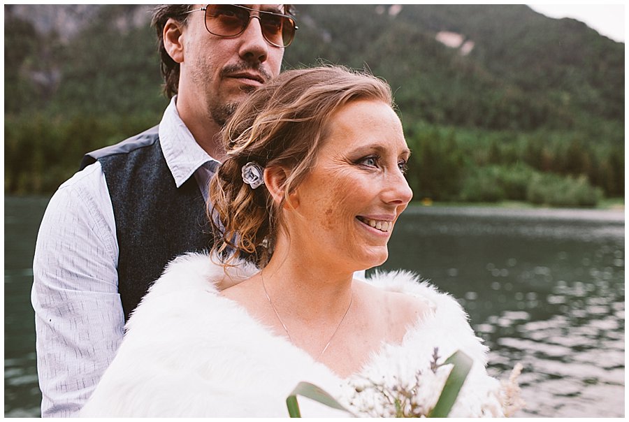 St Johann in Tirol Elopement Nikki and Chris embrace by a mountain lake by Wild Connections Photography