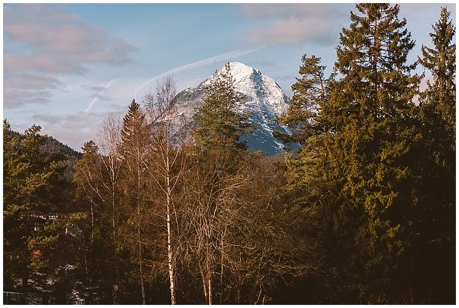 Seefeld Wedding Green trees with a snow covered mountain peak in the background by Wild Connections Photography
