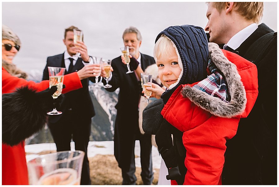 The young nephew looks in to the camera as the adults raise their champagne glasses to toast