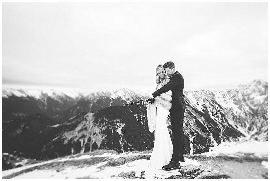 Steph and Lee embrace with a mountain panorama behind them
