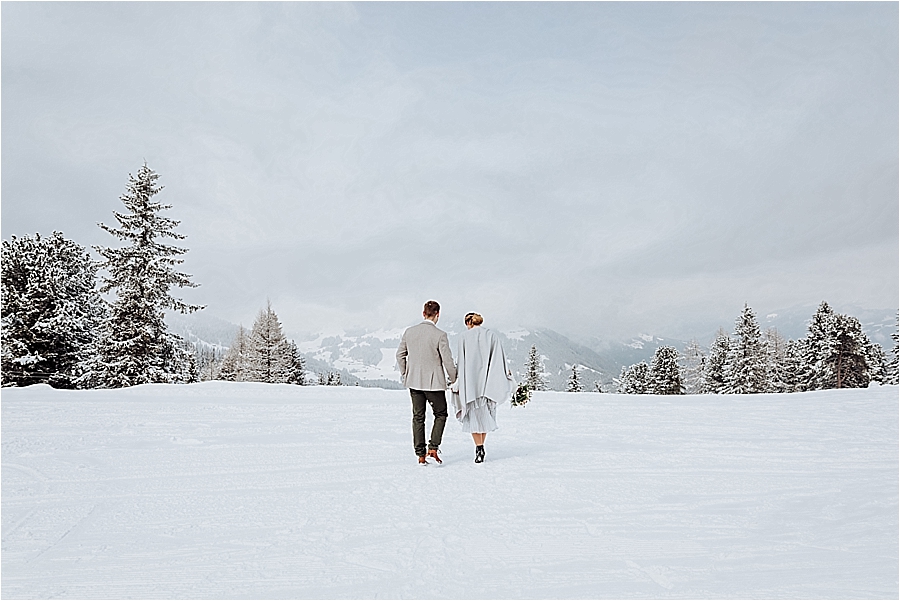 Winter mountain elopement in Mayrhofen Austria by Wild Connections Photography couple walk away in the snow with the mountains behind them