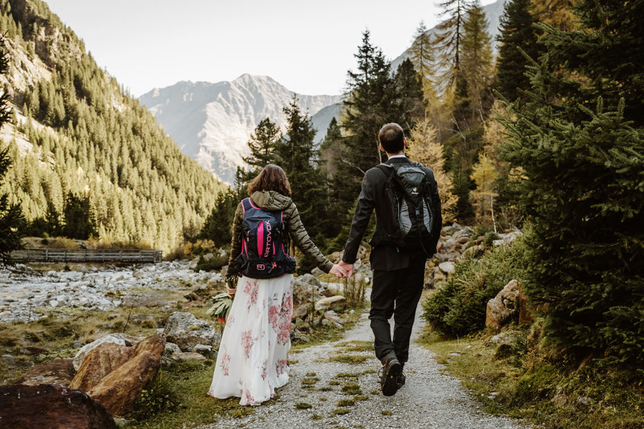 Hiking elopement in Tirol bride and groom hike through a mountainous valley