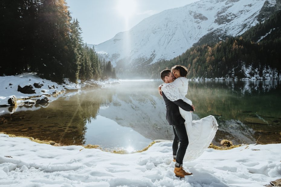 Bride and groom in the snow by a mountain lake during a winter hiking elopement in the Austrian Alps