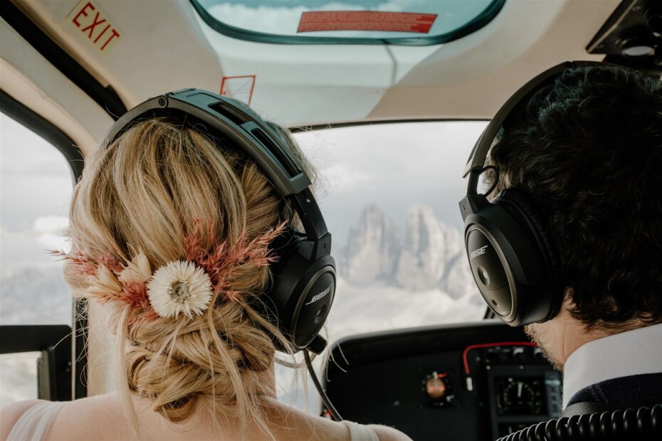 Bride and groom in a helicopter cockpit as it flies over the Dolomites in Italy on their honeymoon