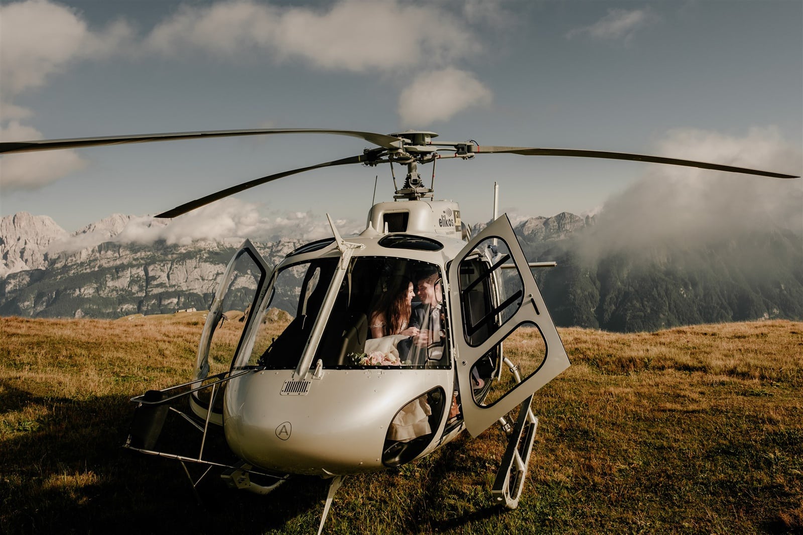 Bride and groom sit in the cockpit of a helicopter for their Dolomites elopement.