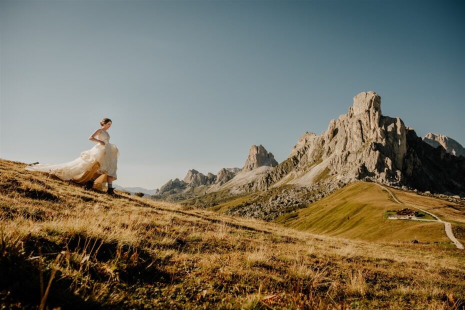 Bride running down a grassy hillside on Passo Giau in the Dolomites
