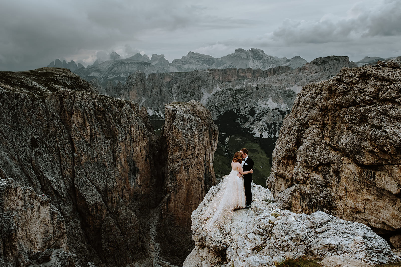Bride and groom in wedding clothes standing on the edge of a mountain after their mountain wedding ceremony in Italy