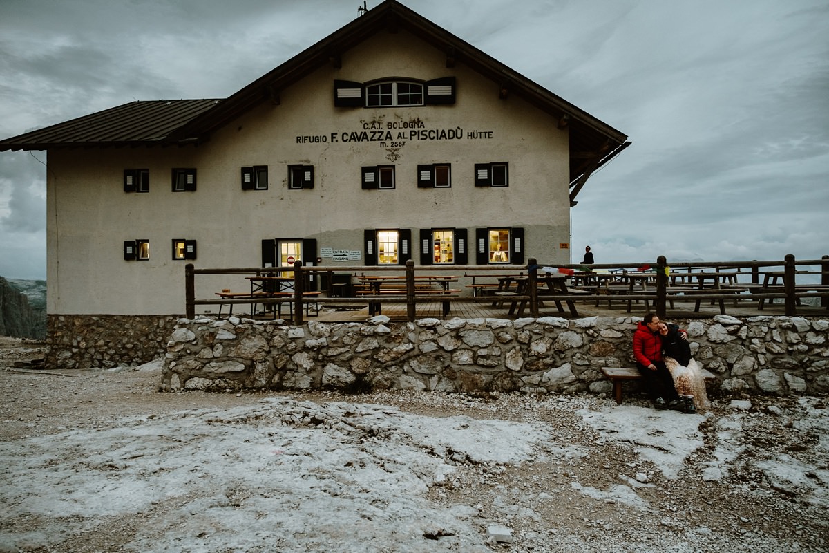 Bride and groom cuddle outside a mountain hut in the Dolomites after their elopement wedding