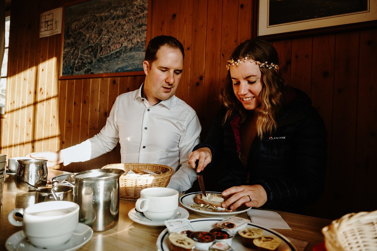 Bride and groom eat bread and jam for breakfast in a mountain hut after their elopement in the Dolomites