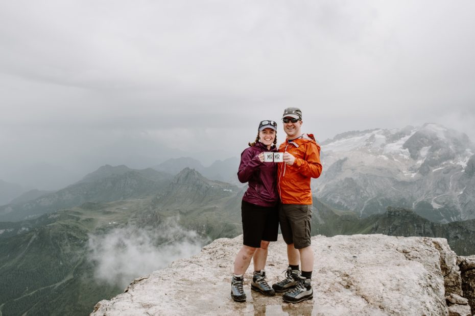 Bride and groom drink prosecco from Mr & Mrs camping mugs after their mountain climbing elopement in the Dolomites