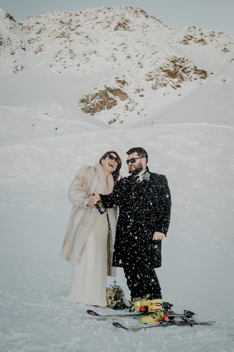 bride and groom spray champagne at the side of a ski slope in St Anton in Austria