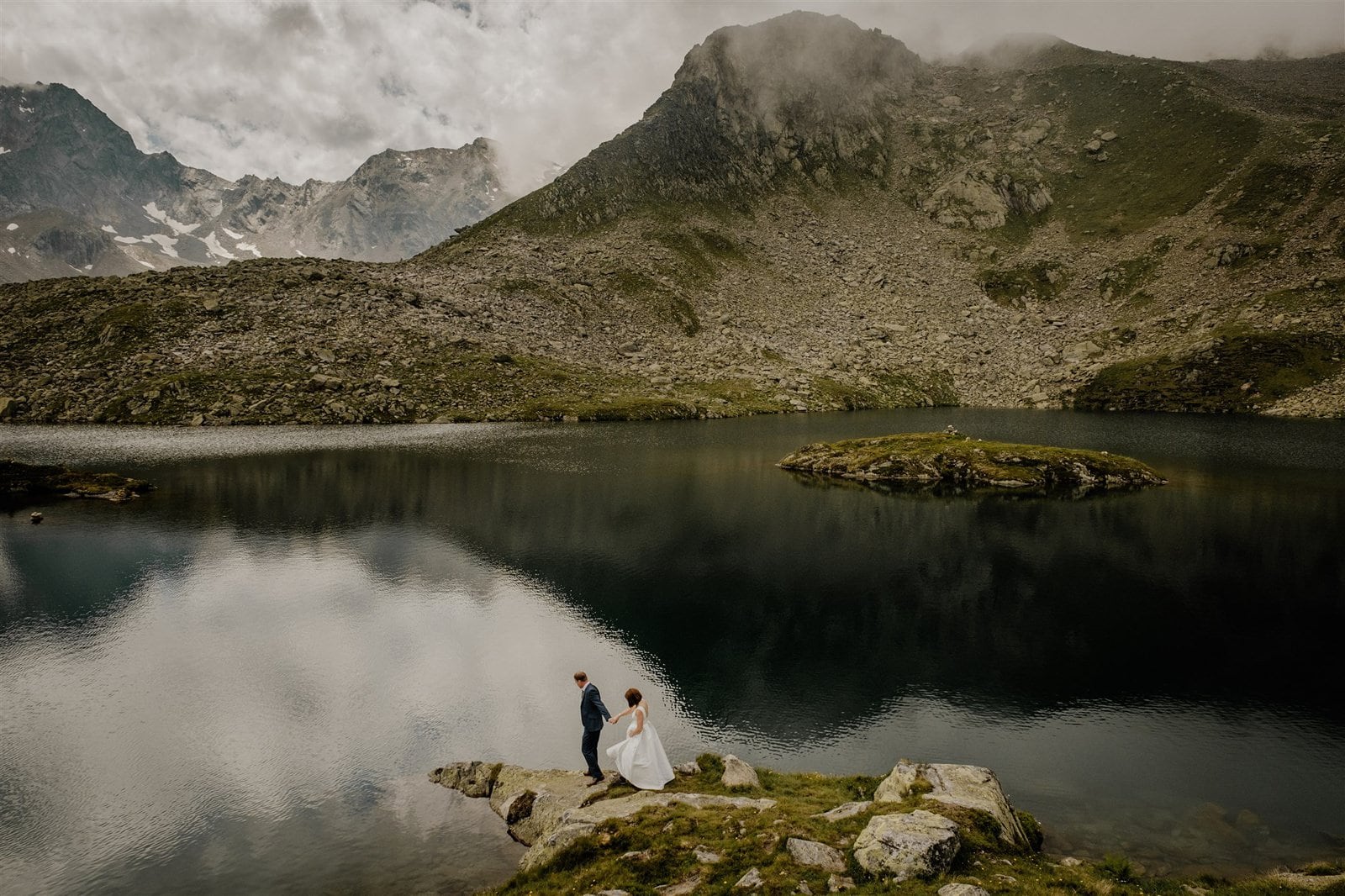 Bride and groom walk along an alpine lake in the tirol region of Austria