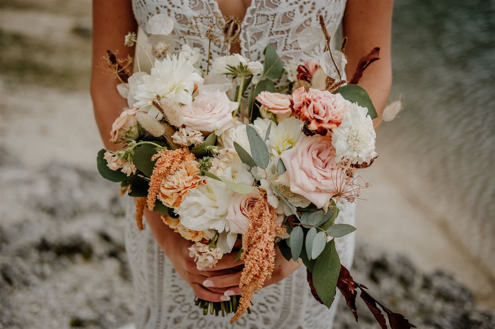 Close up of a bride holding a bouquet of green, white and blush pink flowes