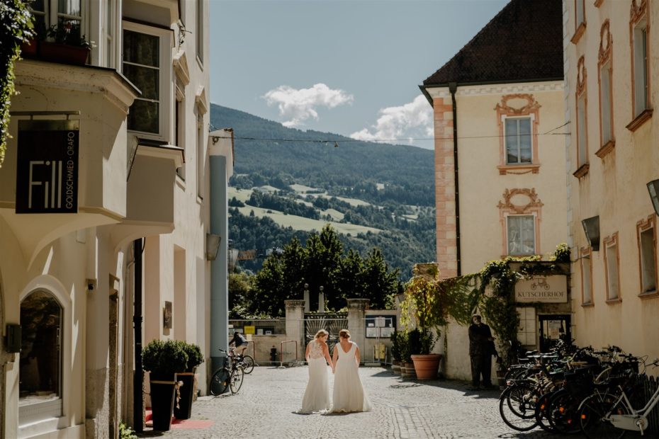 Two brides explore one of the small towns of the Dolomites after their wedding