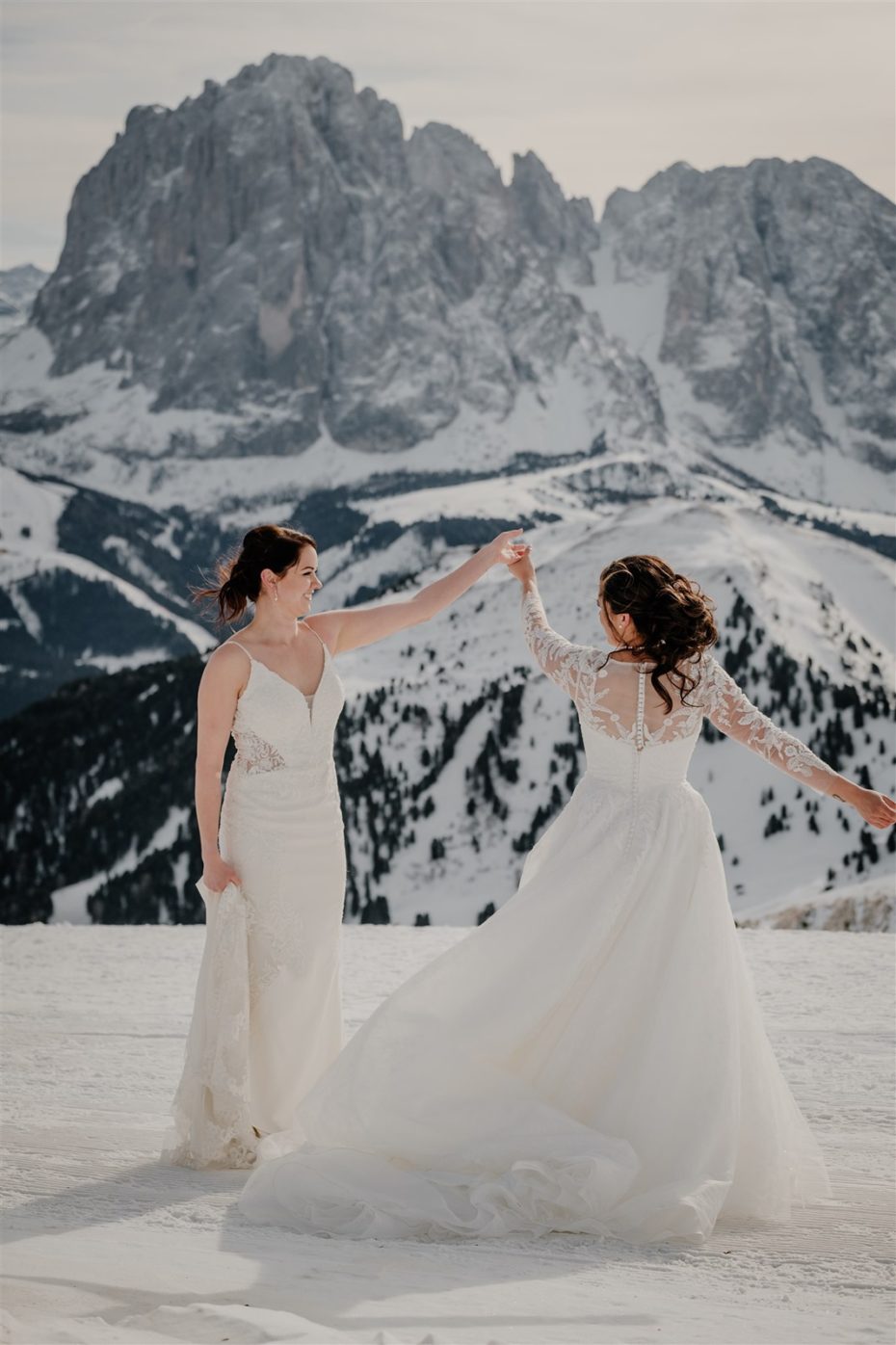 Lesbian brides dance in the snow in the Dolomite mountains in Italy
