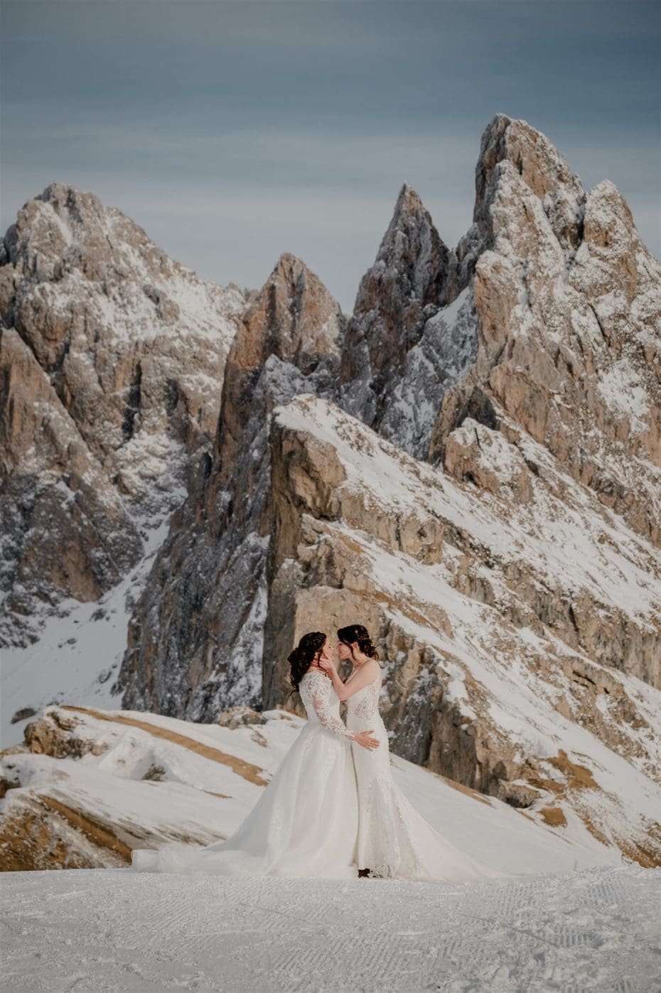 LGBT elopement two brides kiss in front of a dramatic mountain in the Dolomites