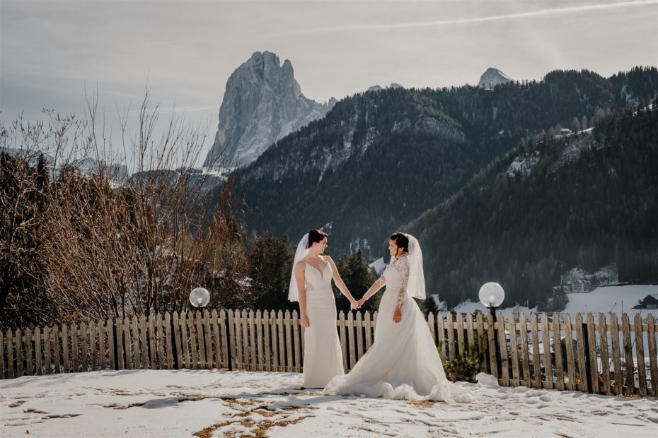 two brides share a first look moment against a winter backdrop in the Dolomites in Italy