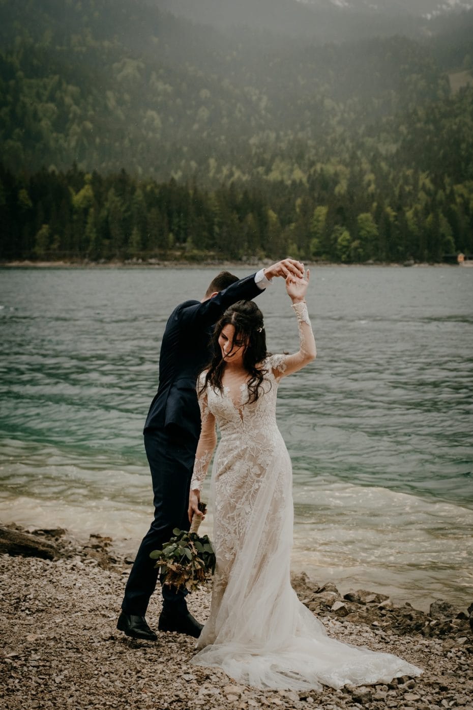 Bride and groom dance on the shore of lake Eibsee in the rain