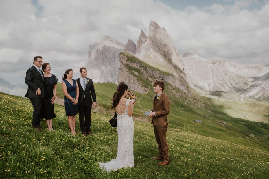 Bride and groom exchange wedding vows in a small elopement ceremony with 5 witnesses on the hillside of the Seceda ridgeline in the Dolomite mountains in Italy
