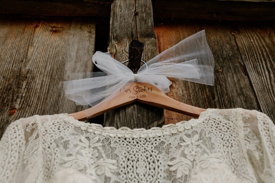 Close up of lace wedding dress on a wooden personalised hanger